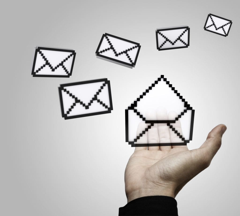 a hand is holding an envelope in front of five mail boxes