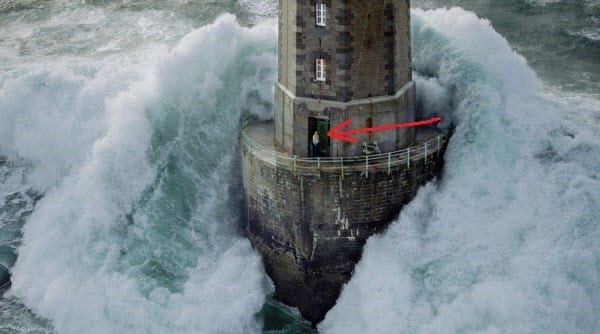 an aerial view of a lighthouse surrounded by waves