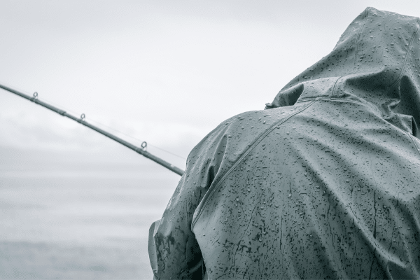 a person in a raincoat holding a fishing rod