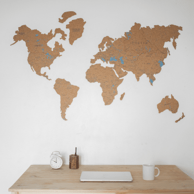 a wooden table with a laptop and a world map on the wall