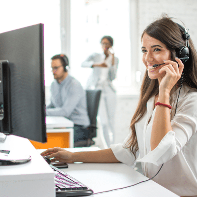 a woman sitting in front of a computer talking on a phone