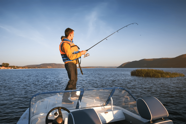 a man standing on the back of a boat holding a fish