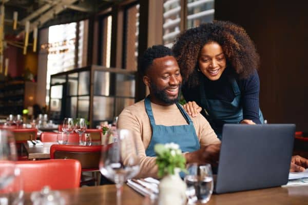 a man and woman sitting at a table with a laptop