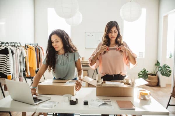 two women in a clothing store looking at their laptops