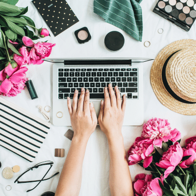 a person typing on a laptop surrounded by flowers